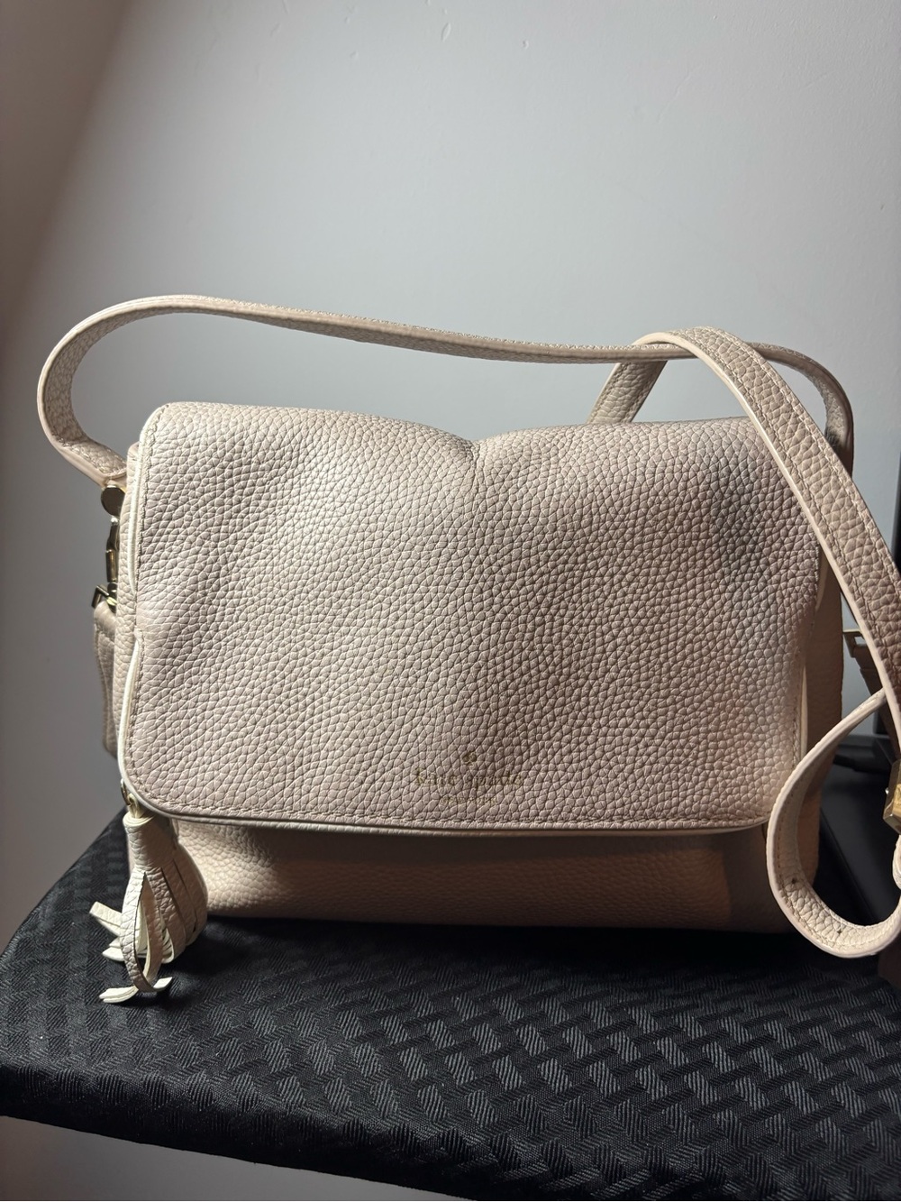 cream-colored Kate Spade pebbled leather flap shoulder bag featuring a tassel